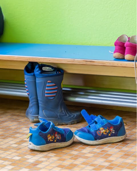 Gummistiefel und Schuhe in Garderobe der Kita