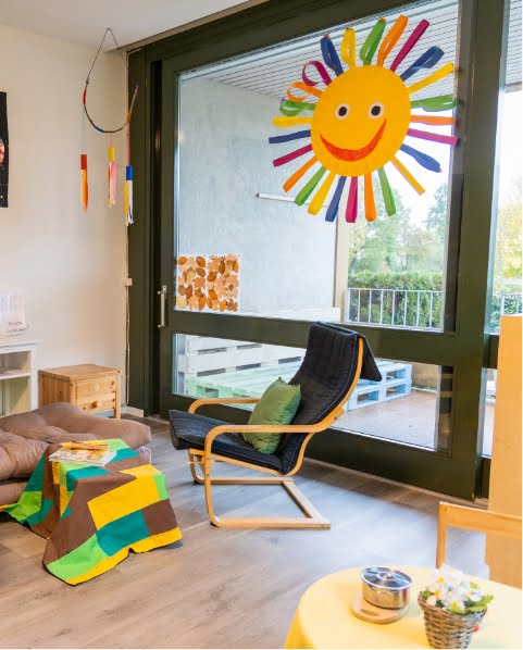 Raum mit Stuhl und grossem Fenster mit gebastelter Sonne in den Tagesstrukturen