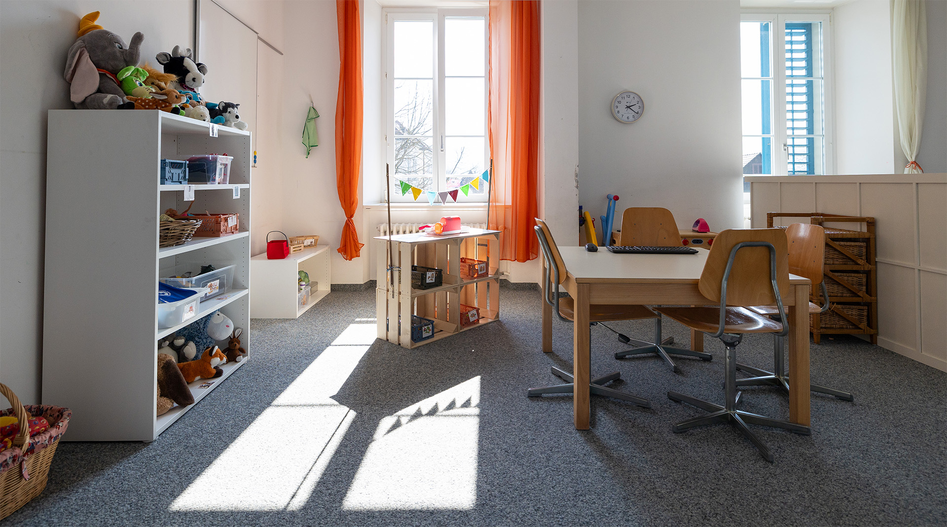 Kindgerecht eingerichteter Spielbereich der Tagesstrukturen Würenlos mit Spielsachen, Tischen und hellem Raumkonzept.