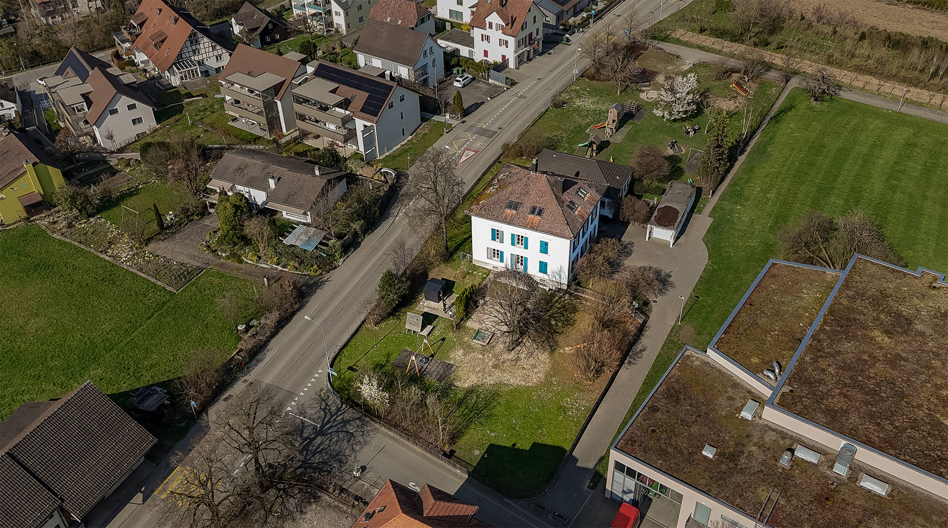 Luftaufnahme der Tagesstrukturen Würenlos mit Gebäude, Garten und Umgebung.