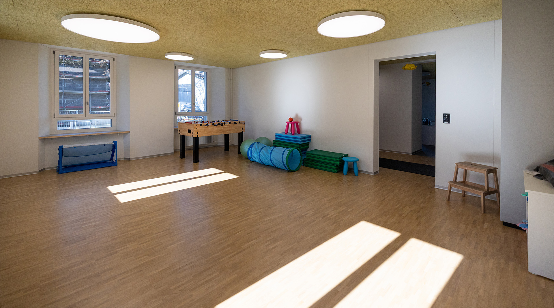Heller Bewegungs- und Spielraum der Tagesstrukturen Wohlen Halde mit viel freier Fläche, Tischfussball, Spielmaterialien und kindgerechter Bewegungslandschaft.